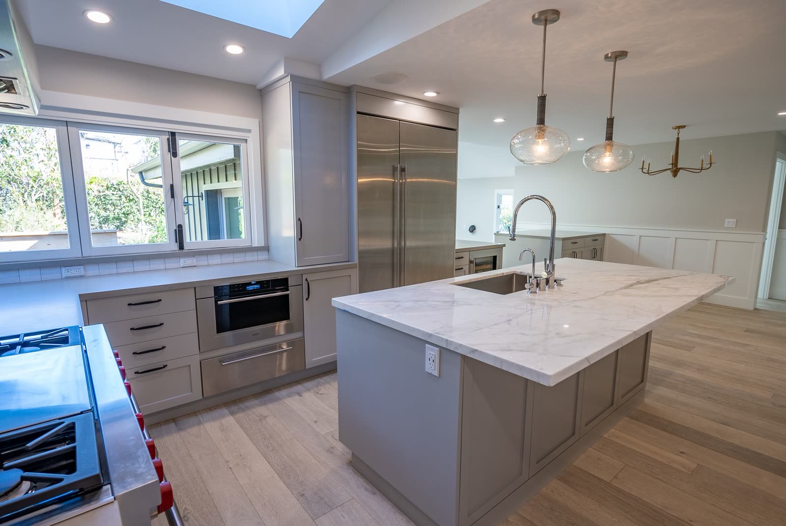 Kitchen with pale cabinetry, a marble island and pendant lighting